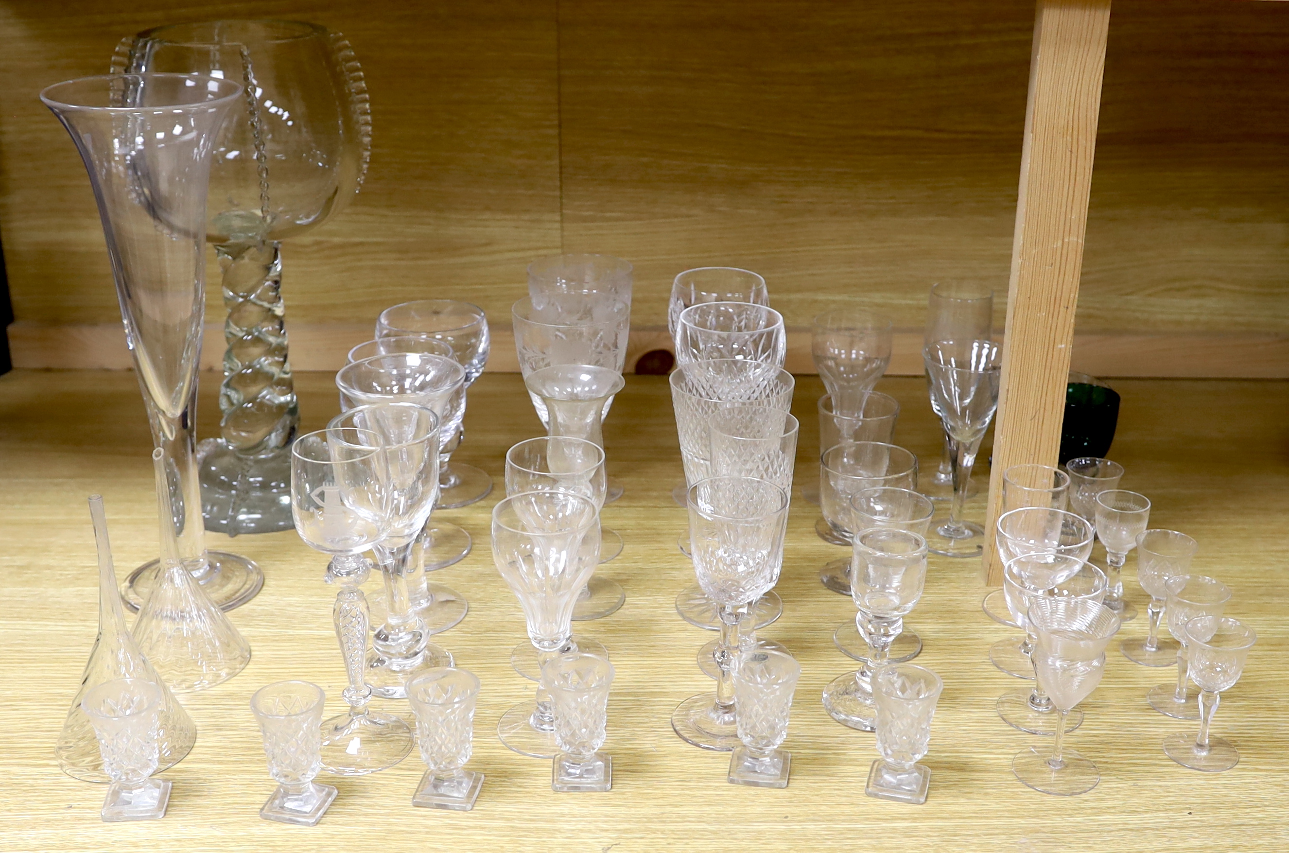 A large glass centrepiece, a teardrop trumpet shaped vase and a collection of 19th and 20th century wine and other drinking glasses
